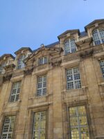 Close-up of a grand Parisian building facade with classic French windows in Le Marais guided tour