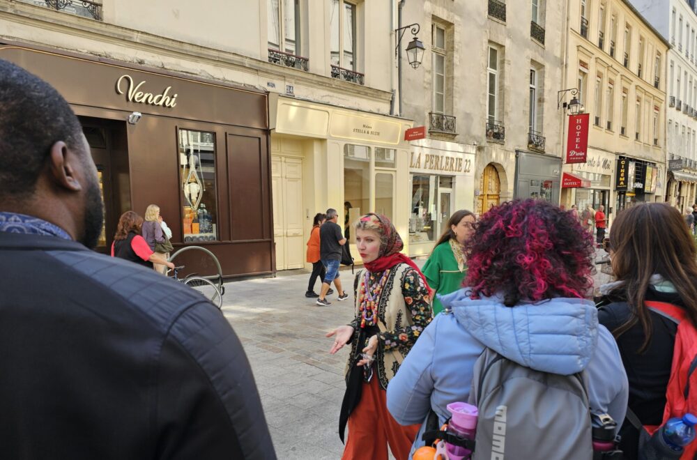 Group of tourists walking through a lively Parisian street during the Le Marais tour.