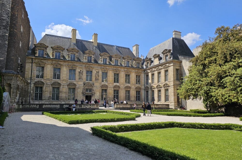 Peaceful garden courtyard at Place des Vosges with historic buildings in the background.