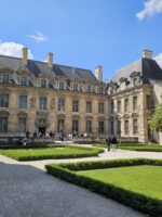 Peaceful garden courtyard at Place des Vosges with historic buildings in the background.