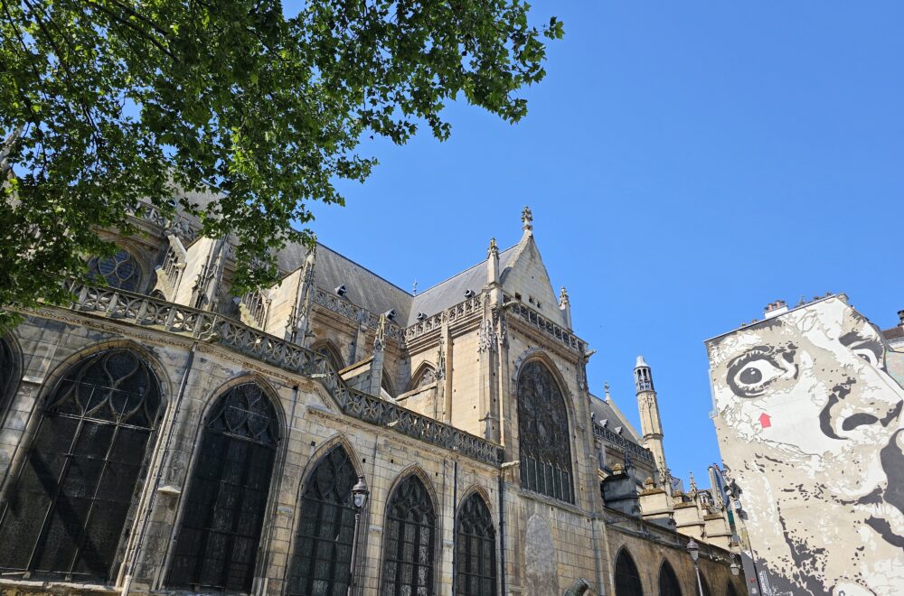Contrasting view of Saint-Merri Church and colorful street art mural in Le Marais.