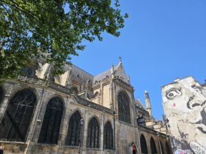 Contrasting view of Saint-Merri Church and colorful street art mural in Le Marais.