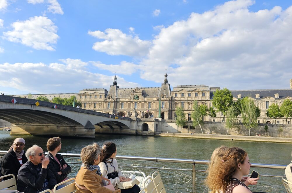 Golden hour view of the Louvre and riverbank as seen from a boat in the river Seine.