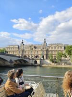 Golden hour view of the Louvre and riverbank as seen from a boat in the river Seine.