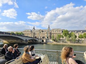 Golden hour view of the Louvre and riverbank as seen from a boat in the river Seine.