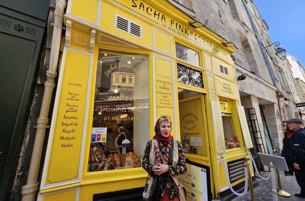 Tour guest standing outside a bright yellow storefront on a Le Marais walking tour.