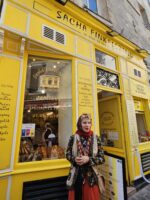 Tour guest standing outside a bright yellow storefront on a Le Marais walking tour.