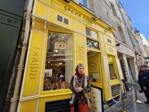 Tour guest standing outside a bright yellow storefront on a Le Marais walking tour.