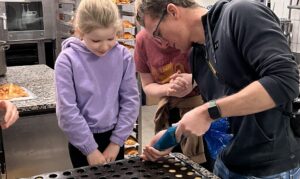 Father and daughter piping into tray