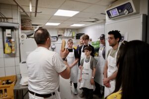 Teacher showing bread to guests during French Insider Baking Experience