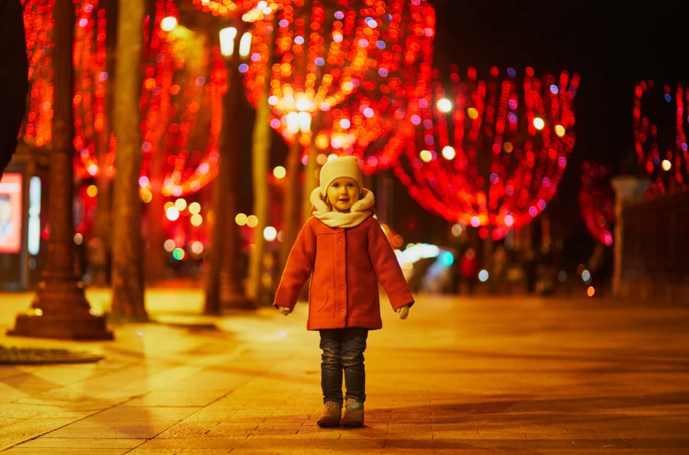 Preschooler girl on Champs Elysees with its traditional Christmas illumination in Paris, France