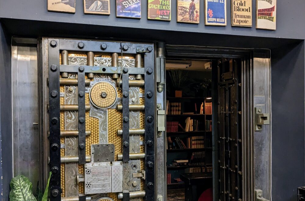 Entrance to The Last Bookstore in Los Angeles, featuring its iconic vault door and display of book-themed posters above.