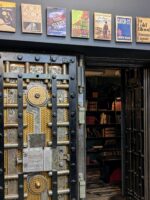 Entrance to The Last Bookstore in Los Angeles, featuring its iconic vault door and display of book-themed posters above.