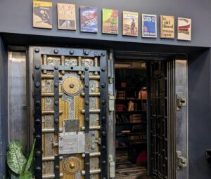 Entrance to The Last Bookstore in Los Angeles, featuring its iconic vault door and display of book-themed posters above.