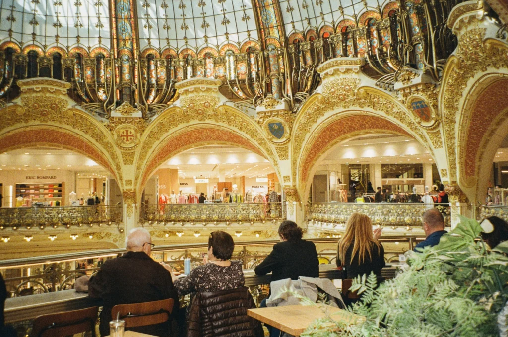 A group of people sitting at tables in a restaurant inside Galeries Lafayette