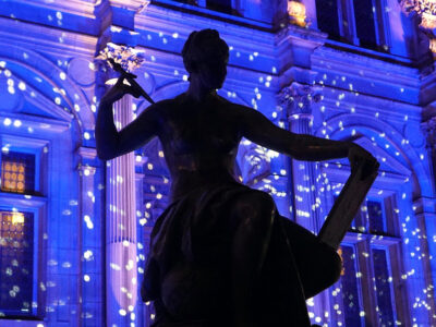 Statue in front the Hôtel de Ville in Paris lit with holiday lights