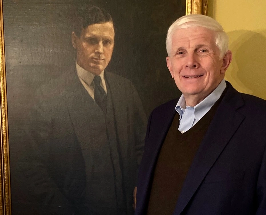 Robert Billingsley posing with a portrait of his father, Logan