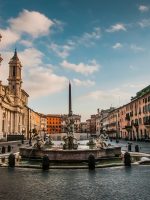 a canal with buildings along it with Piazza Navona in the background